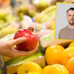 Dłoń trzymająca granat na tle owoców i wizerunku mężczyzny.