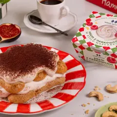 Tiramisu z kremem nerkowcowym w stylu mascarpone, obok opakowanie kremu i figi.